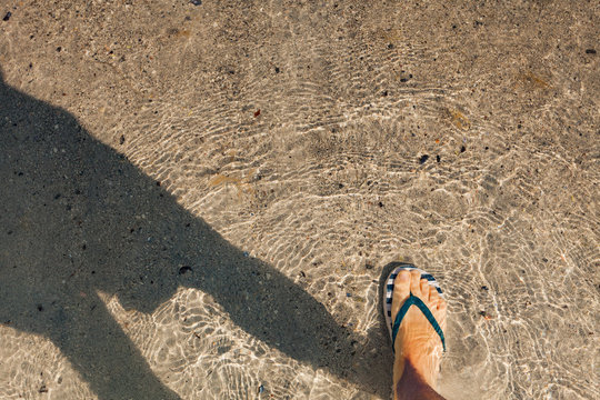 Female feet in flip flop shoes on beach