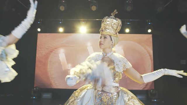 Beautiful girls in royal court costumes and queen dress perform on stage. Modern dance show.