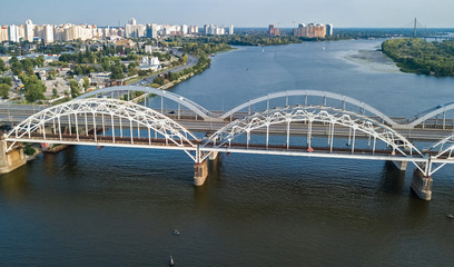 Aerial top view of automobile and railroad Darnitsky bridge across Dnieper river from above, Kiev (Kyiv) city skyline, Ukraine
