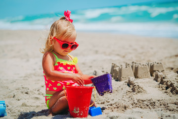 cute little girl play with sand on beach