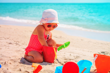 cute little girl play with sand on beach