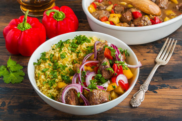 Beef and vegetables stew. White casserole and bowl with meat, bulgur, red onion and fresh parsley on wooden table