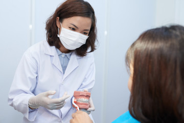Doctor explaining young atient how to brush teeth with braces