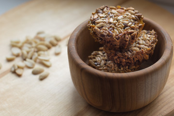 Roasted gozinaki from sunflower seeds in wooden bowl on wooden background. Front view.
