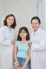 Portrait of happy Vietnamese dentists and their teenage patient smiling at camera