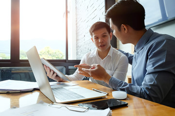 Two businessman working with laptop computer and finance report.