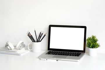 Workplace empty laptop display and office supply with green plant on table.