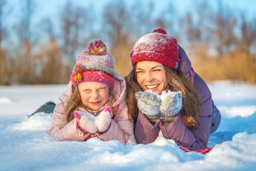 Little girl and her mother playing outdoors at sunny winter day