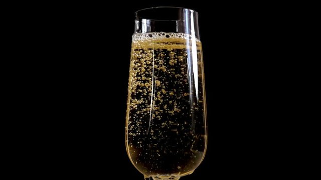 Champagne fluctuates and foams in the glass in Slow Motion on a black background 