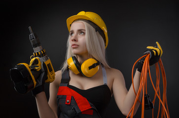 girl in construction clothes and protective equipment posing with a screwdriver