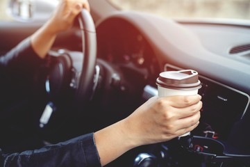 people person drinking paper cup coffee of hot holding hand in a car in the morning not sleepy be energetic while driving. transportation and vehicle concept. empty copy space for text.