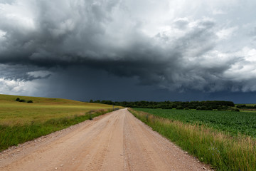 Fototapeta na wymiar Rural gravel road under stormy summer clouds.