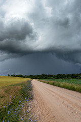 Fototapeta na wymiar Rural gravel road under stormy summer clouds.