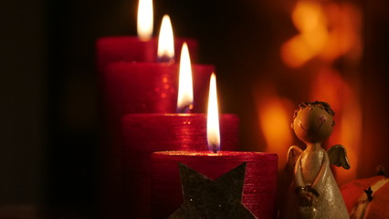 4 brennende rote Kerzen nah vor dunklem Hintergrund