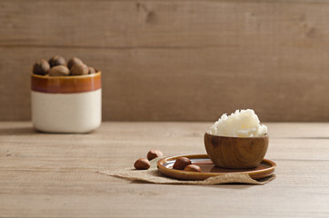 Shea butter and nuts on a wooden board, copy space.