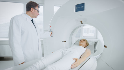 In Medical Laboratory Radiologist Controls MRI or CT or PET Scan with Female Patient Undergoing Procedure. Professional Doctor Conducts Emergency Checkup Procedure with Advanced Medical Technologies.