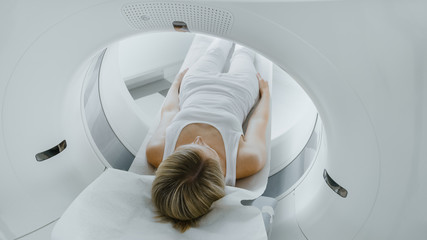 Female Patient Lying on a CT or MRI Scan, Bed is Moving inside Machine Scanning Her Body and Brain. In Medical Laboratory with High-Tech Equipment. - obrazy, fototapety, plakaty