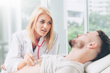 Woman doctor is talking and examining male patient in hospital office. Healthcare and medical...
