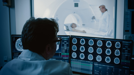 In Medical Laboratory Patient Undergoes MRI or CT Scan Process under Supervision of Radiologist, in Control Room Doctor Watches Procedure and Monitors Brain Activity. - obrazy, fototapety, plakaty
