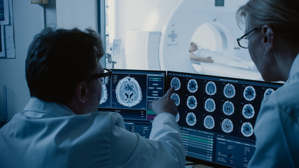 In Control Room Doctor and Radiologist Discuss Diagnosis while Watching Procedure and Monitors...