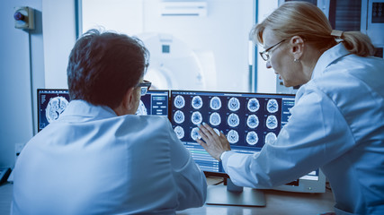 In Control Room Doctor and Radiologist Discuss Diagnosis while Watching Procedure and Monitors...