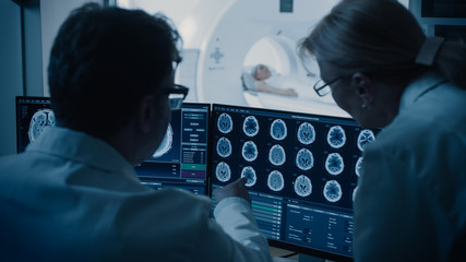 In Control Room Doctor and Radiologist Discuss Diagnosis while Watching Procedure and Monitors...