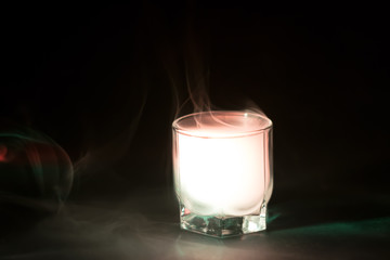 white, green smoke (evaporation) in a glass bowl on a black background