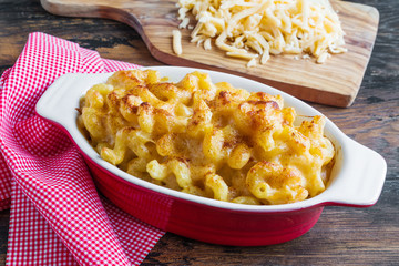 American macaroni dish Mac and Cheese in red and white baking form on wooden rustic table. - 236238657