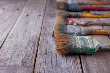 Fototapeta premium Old paintbrushes stained with paint on rustic table