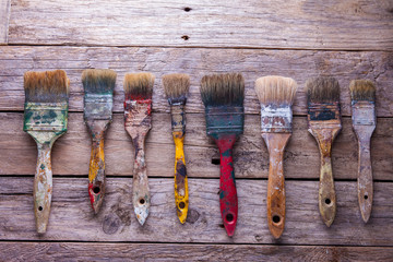 Old paintbrushes stained with paint on rustic table
