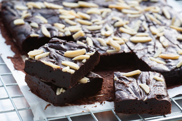 Dark chocolate brownies with almond topping on wire rack.