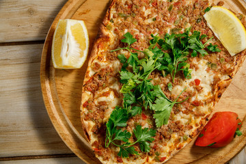 Traditional Turkish food Lahmajun on a wooden tray. View from above.