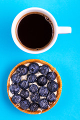 Delicious blueberry tartlet with vanilla cream and cup of coffee