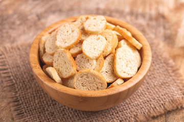 Wheat salted crackers in wooden bowl on burlap napkin