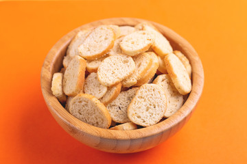Wheat salted crackers in wooden bowl on bright colored background