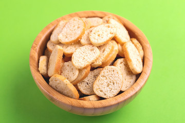 Wheat salted crackers in wooden bowl on bright colored background