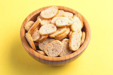 Wheat salted crackers in wooden bowl on bright colored background