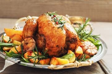 Festive roast chicken with potatoes,garlic and rosemary on wooden rustic table.