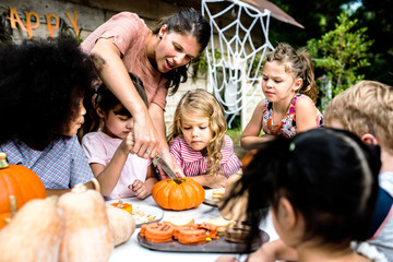 Young kids carving Halloween jack-o'-lanterns