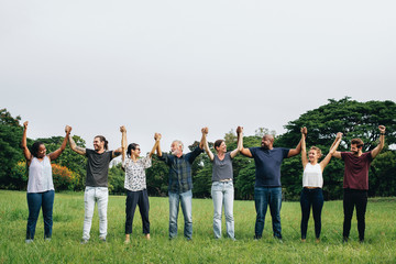 Happy diverse people holding hands in the park