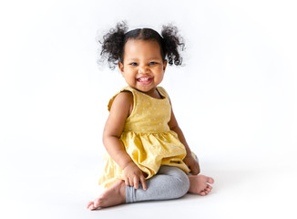 Happy little girl in a yellow dress sitting - obrazy, fototapety, plakaty