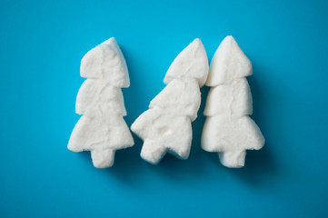 closeup of white marshmallows in shaped fir on blue background