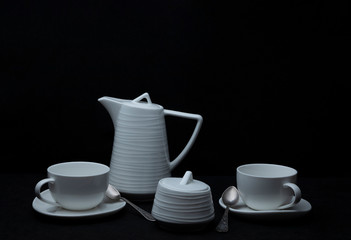 White tea set on a black background.
