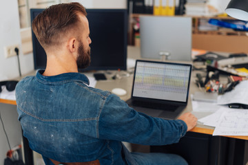 Stylish man working on laptop in messy home office