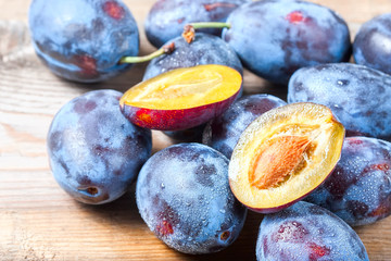 Ripe plums scattered on wooden background.