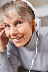 Naklejka premium Frau als Senior hört über Kopfhörer Musik