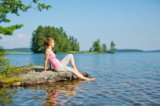 Mid adult woman sitting next to a lake in Finland