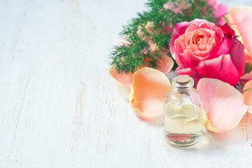 Bottle with essential aroma oil on white wooden background.