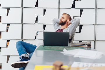 A content man with laptop relaxing in office