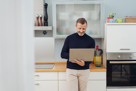 stylish man using a laptop computer in a kitchen